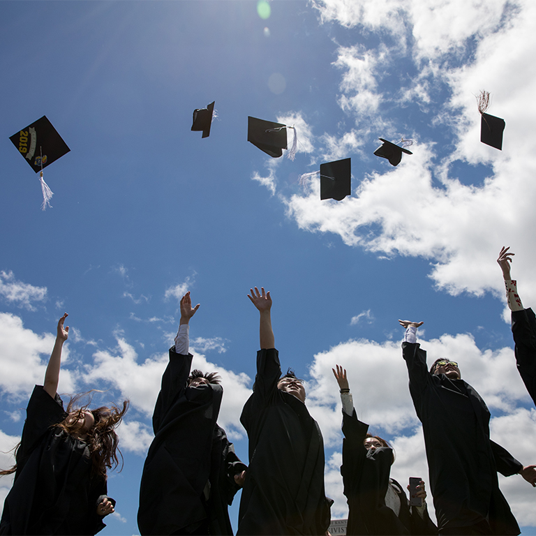 Graduating students throwing caps into air on commencement day